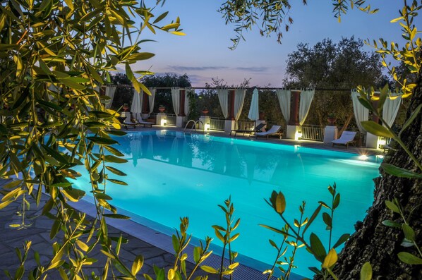 A swimming pool with lounge chairs and umbrellas, surrounded by greenery and trees. - Poggio degli Ulivi (Rodi Garganico)
