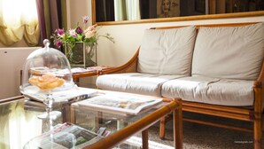 Een woonkamer met een glazen salontafel, een rieten bank en een vaas met bloemen.