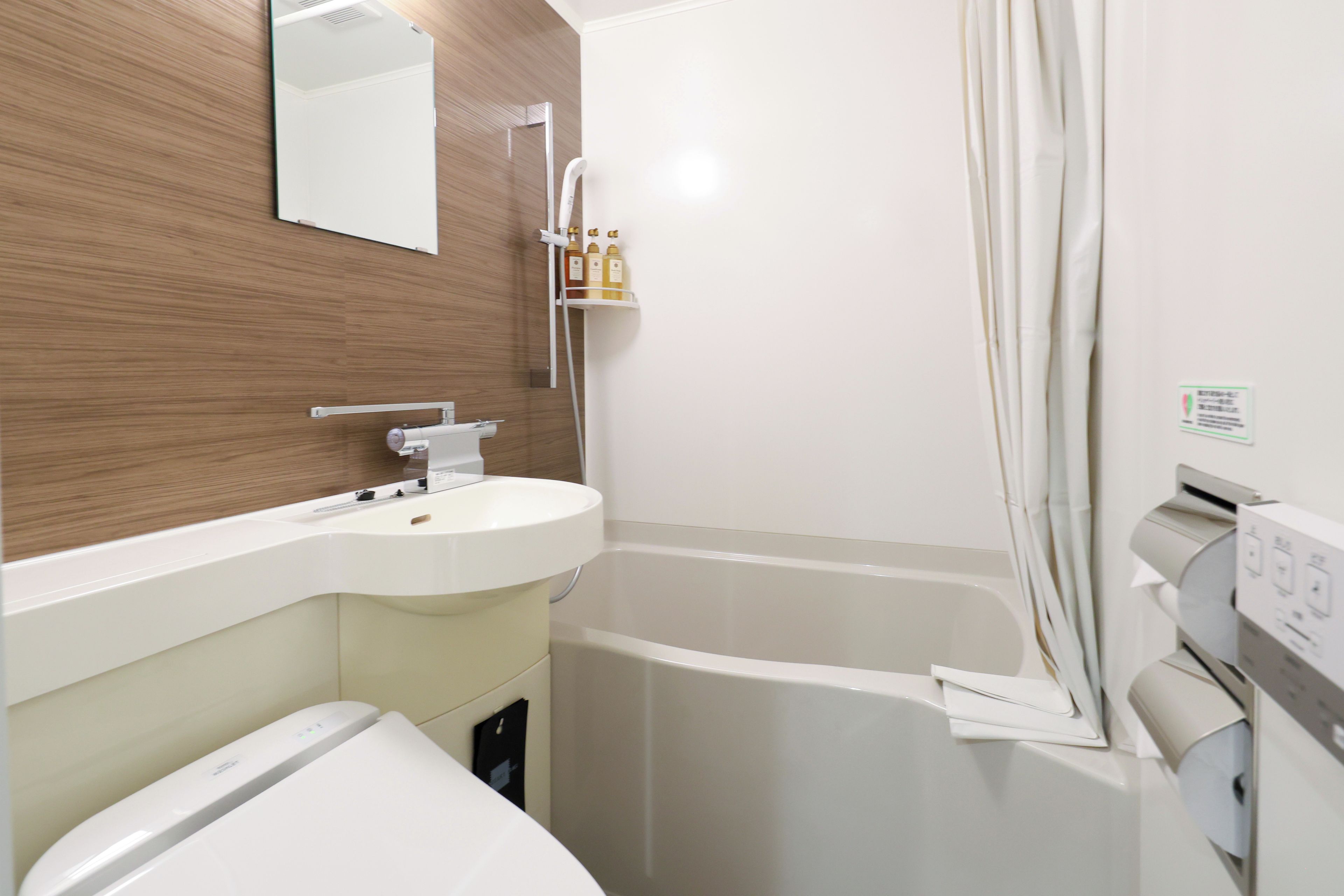 A modern bathroom with a white sink, a toilet, a shower with a curtain, and a mirror on the wall.