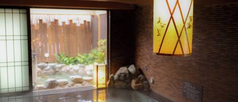 A traditional Japanese room with a tatami mat floor, a wooden door leading outside, and a hanging lantern.