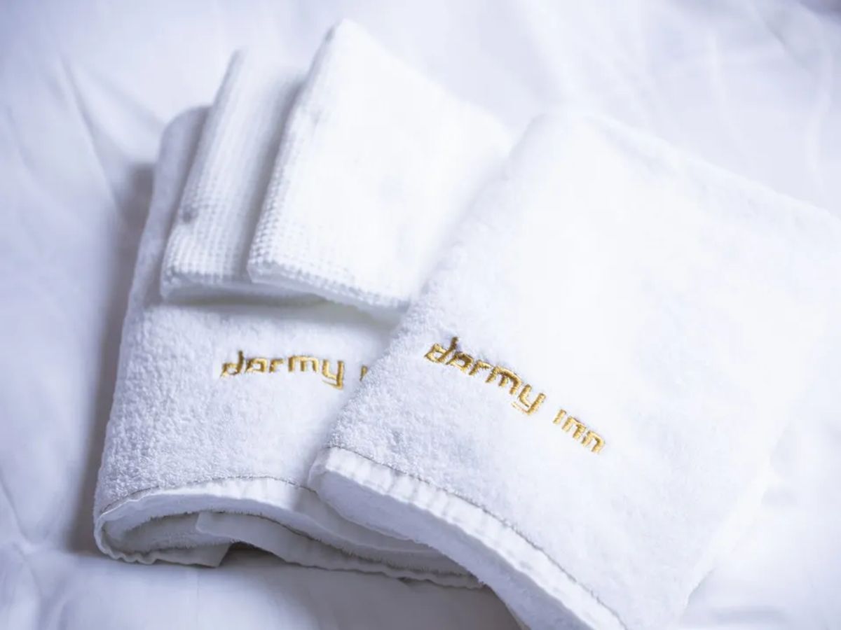 A set of white towels with gold embroidery, folded and placed on a white surface.