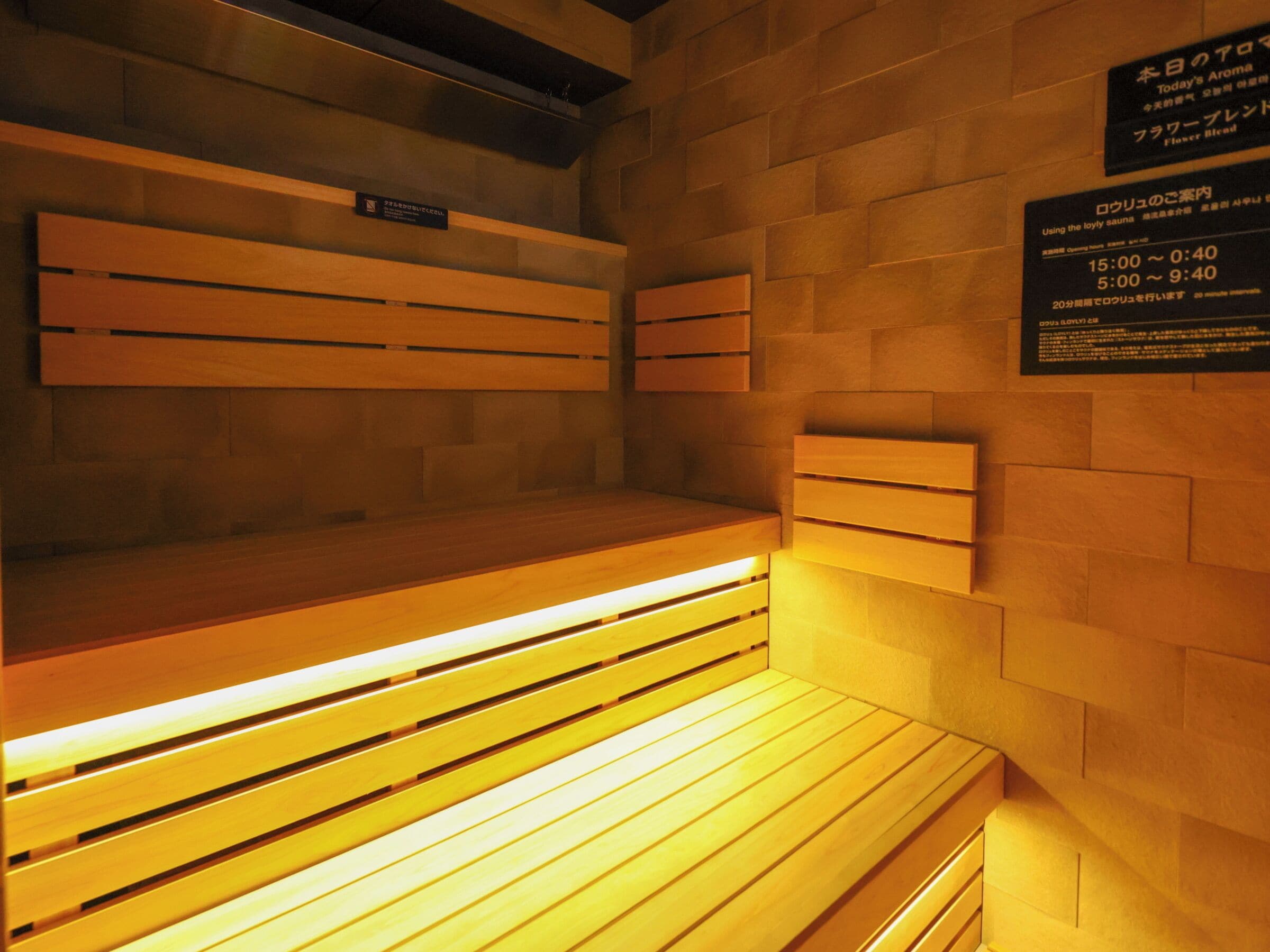 En sauna med træbænke og flisebeklædt væg.