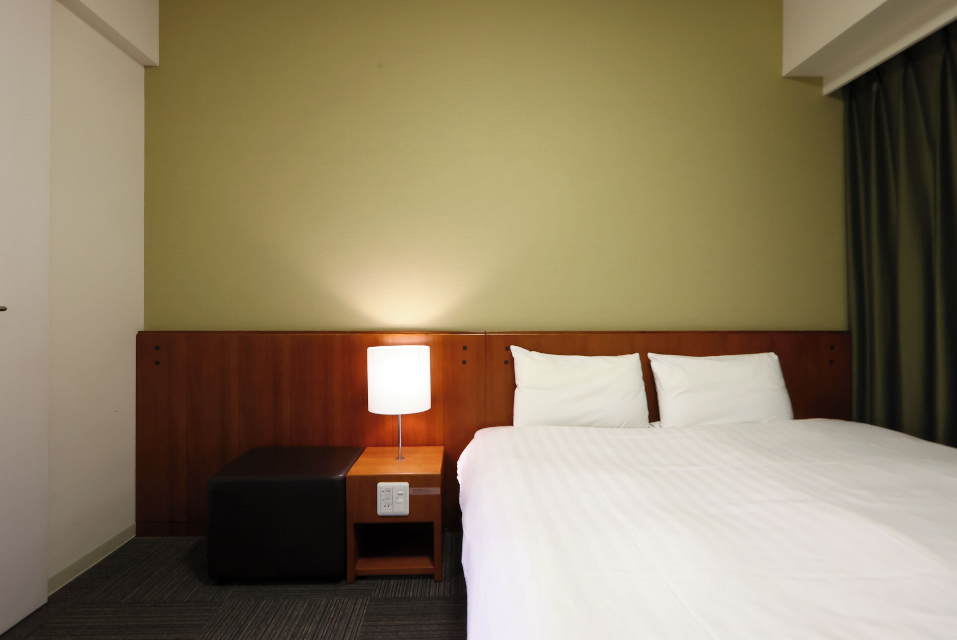 Une chambre d’hôtel avec un lit, une table de chevet avec une lampe et une tête de lit en bois.
