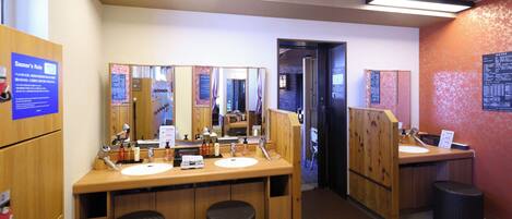 A public restroom with wooden counters, mirrors, and black waste baskets.