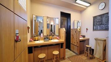 Ein Badezimmer mit Holzschränken, einem Waschbecken, zwei Hocker, einem Spiegel und einer Uhr an der Wand.