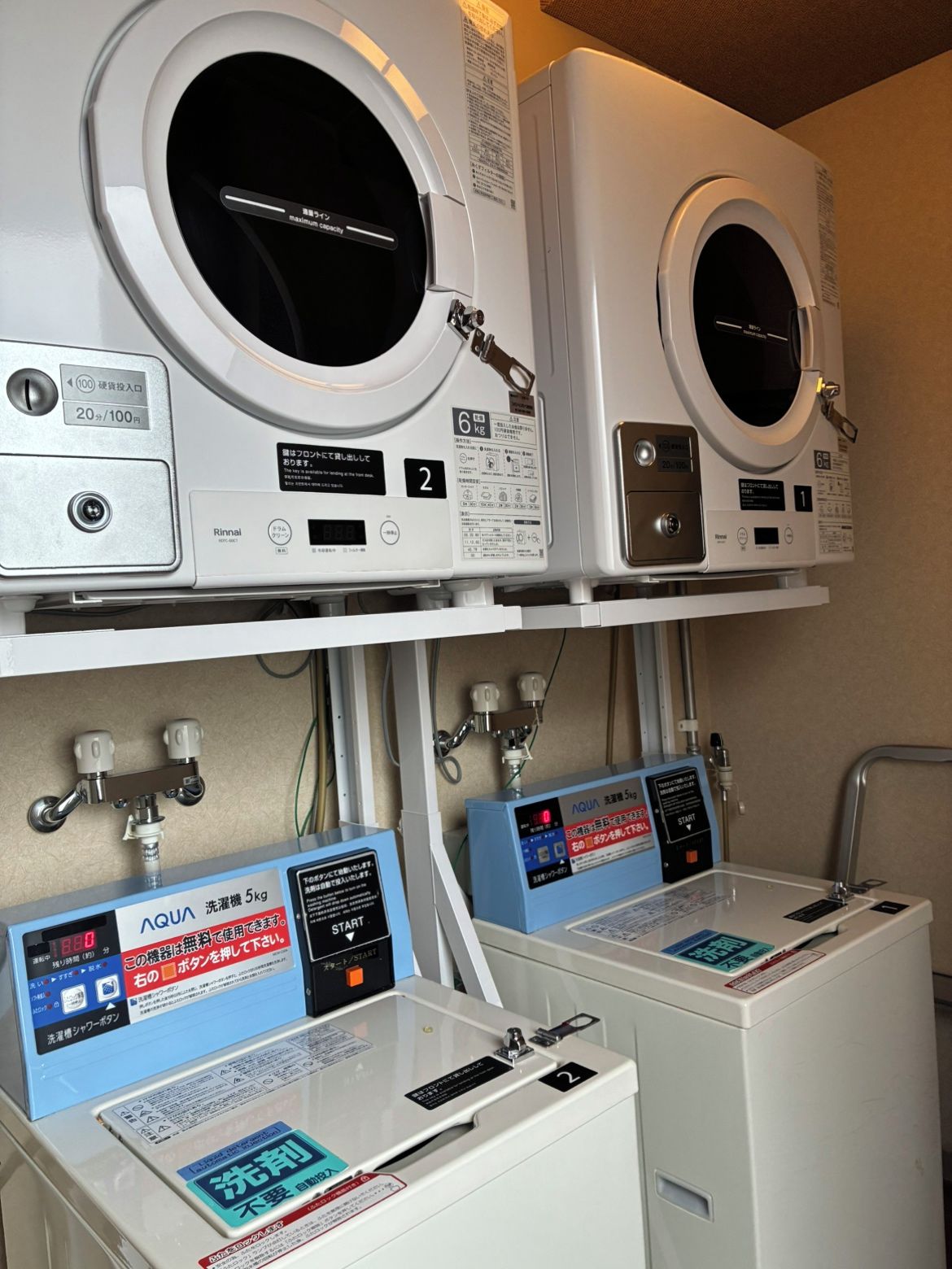 Two stacked washing machines with control panels and a water filtration system below.