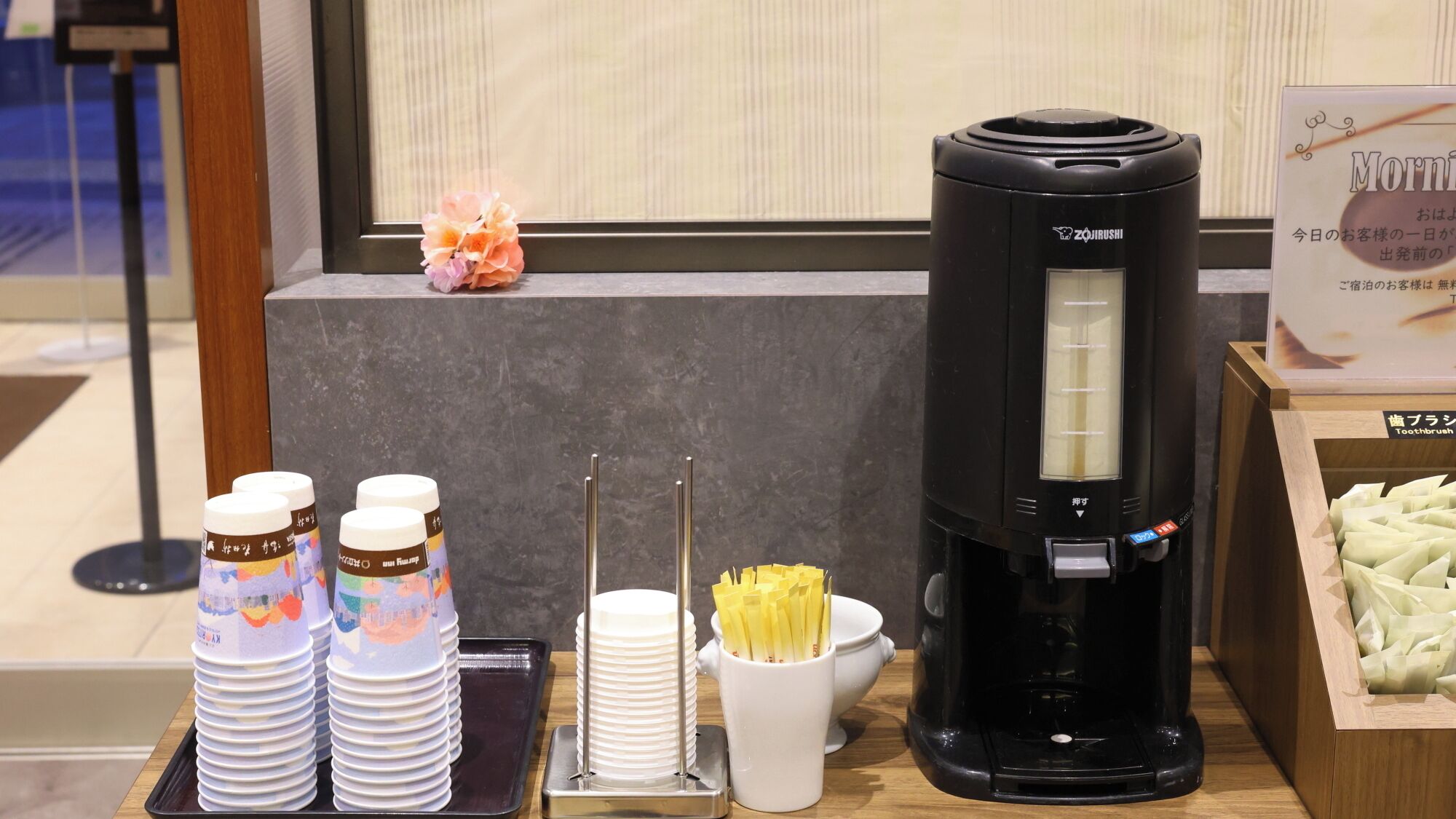 Una cafetera, pilas de platos blancos y un portavasos con cubiertos.