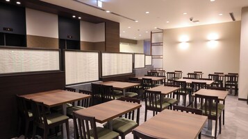 Un restaurante con varias mesas y cabinas, sillas de madera y una decoración interior moderna.