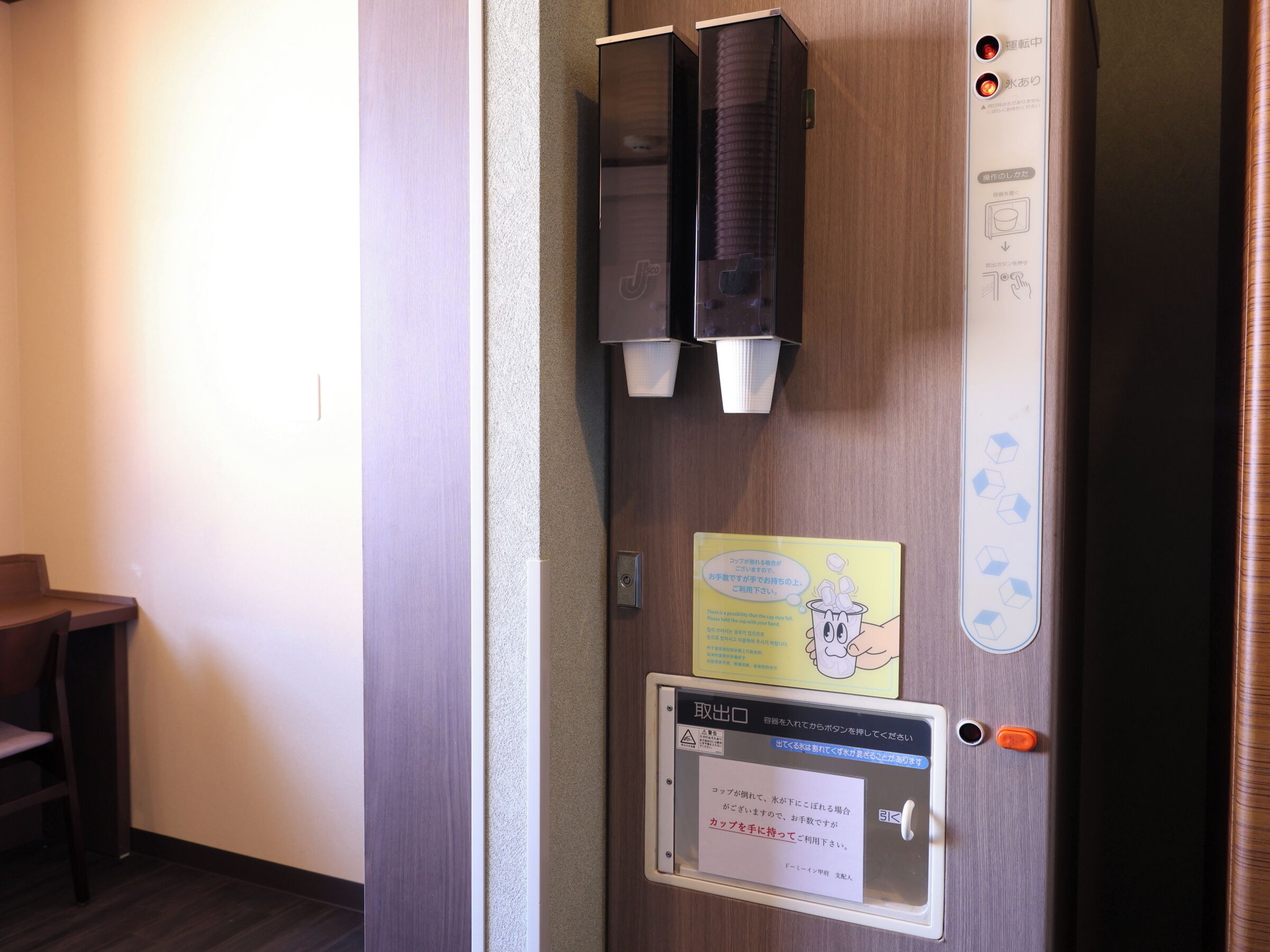 A hotel room door with a towel dispenser, a hand sanitizer dispenser, and a notice about towel usage.