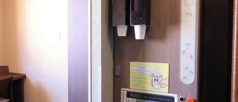 A hotel room door with a towel dispenser, a hand sanitizer dispenser, and a notice about towel usage.