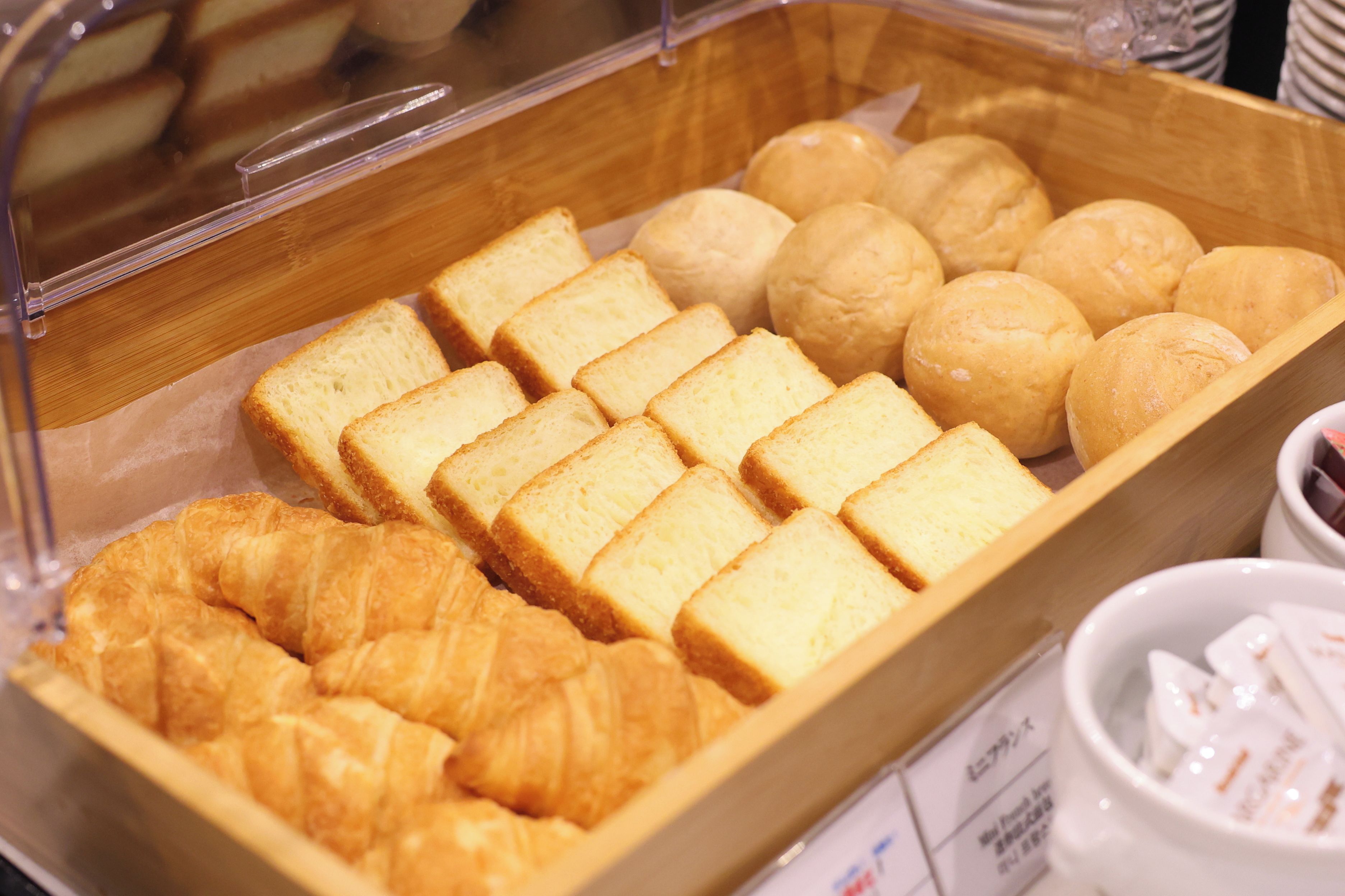 A bakery display case with various baked goods including bread, rolls, and croissants.