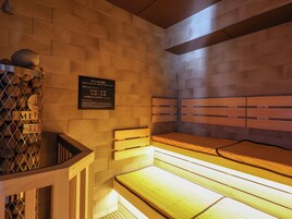 A sauna with a wooden bench and a wall-mounted sign with operating hours.