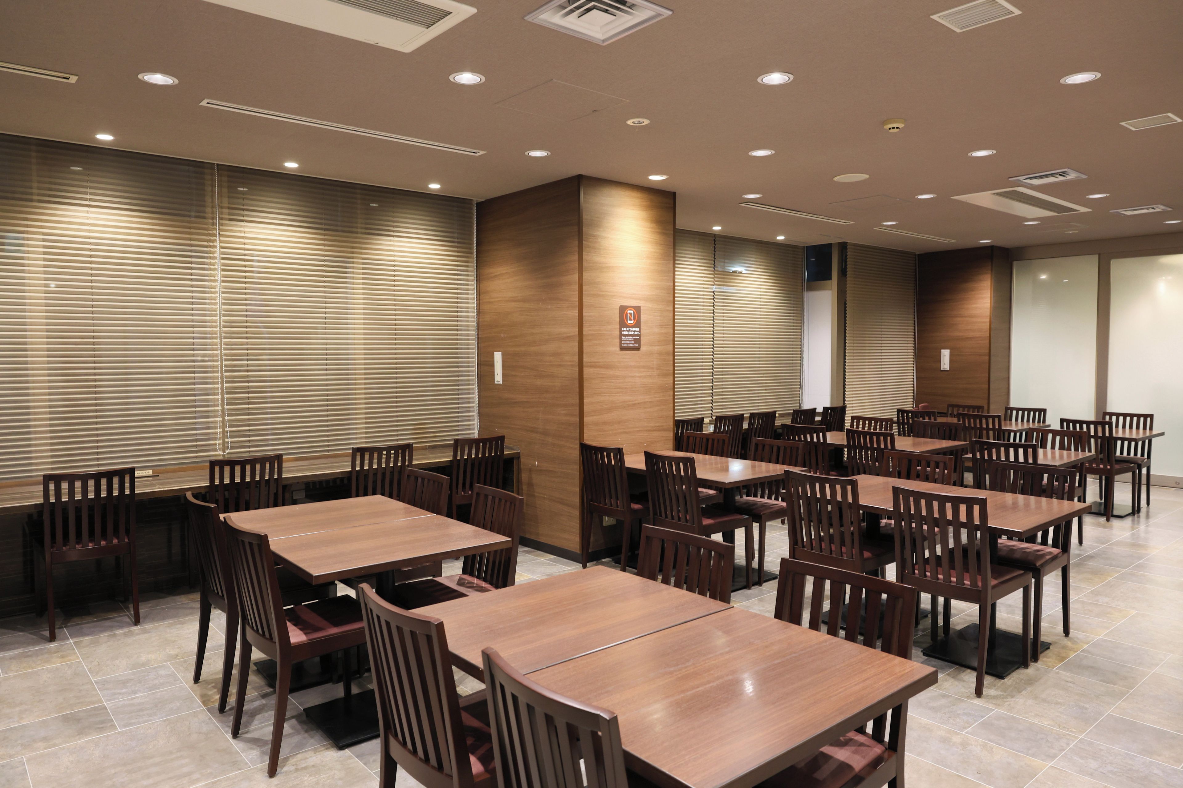 Un salón de conferencias con varias mesas y sillas, equipado con luces en el techo y ventilación.