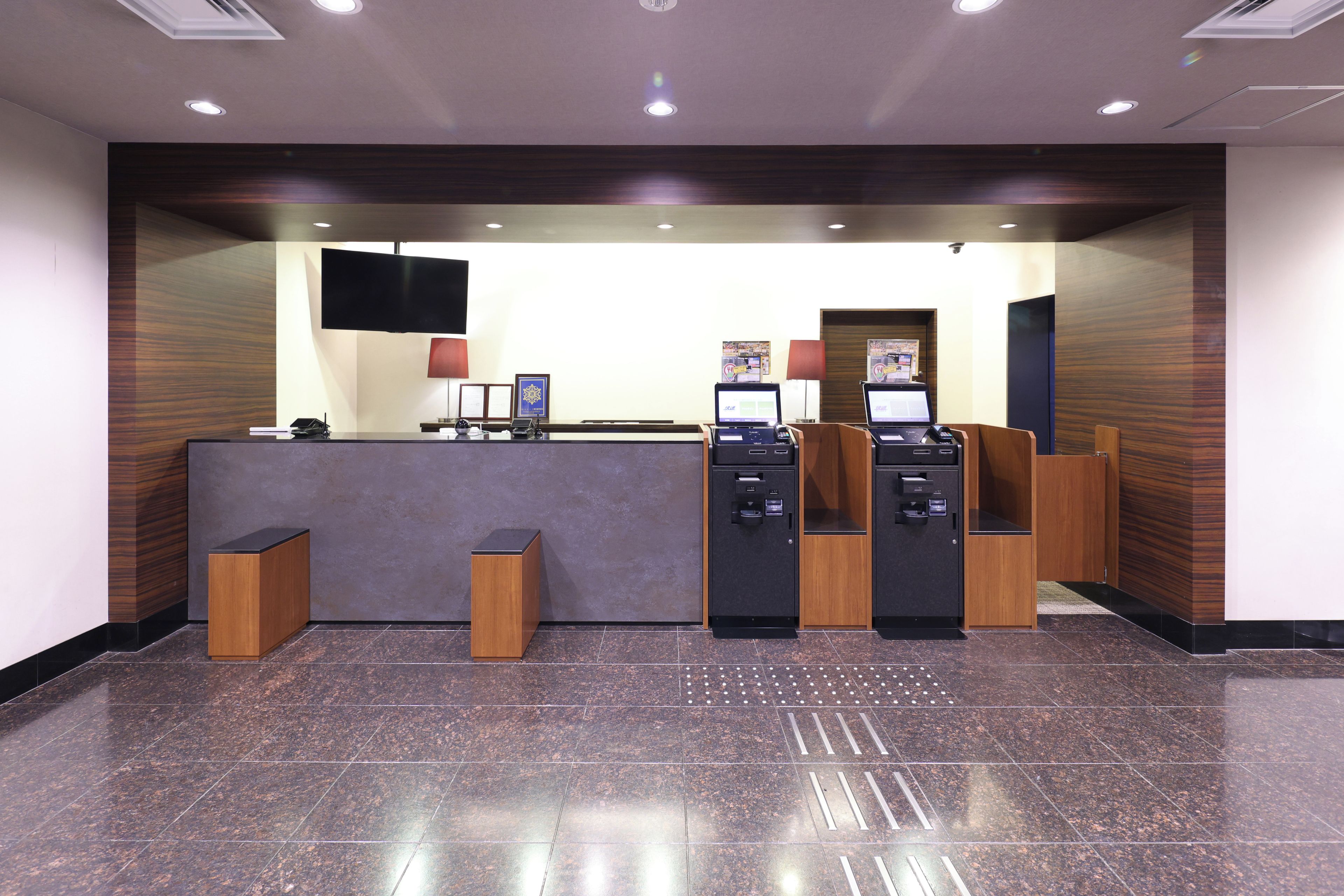 Un'area di accoglienza con reception, due computer, una televisione e uno schermo a parete.