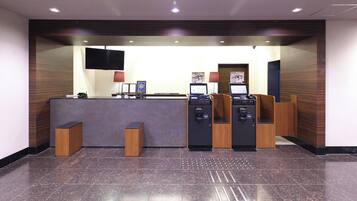 A reception area with a counter, two computers, a television, and a wall-mounted screen.