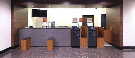 Un'area di accoglienza con reception, due computer, una televisione e uno schermo a parete.