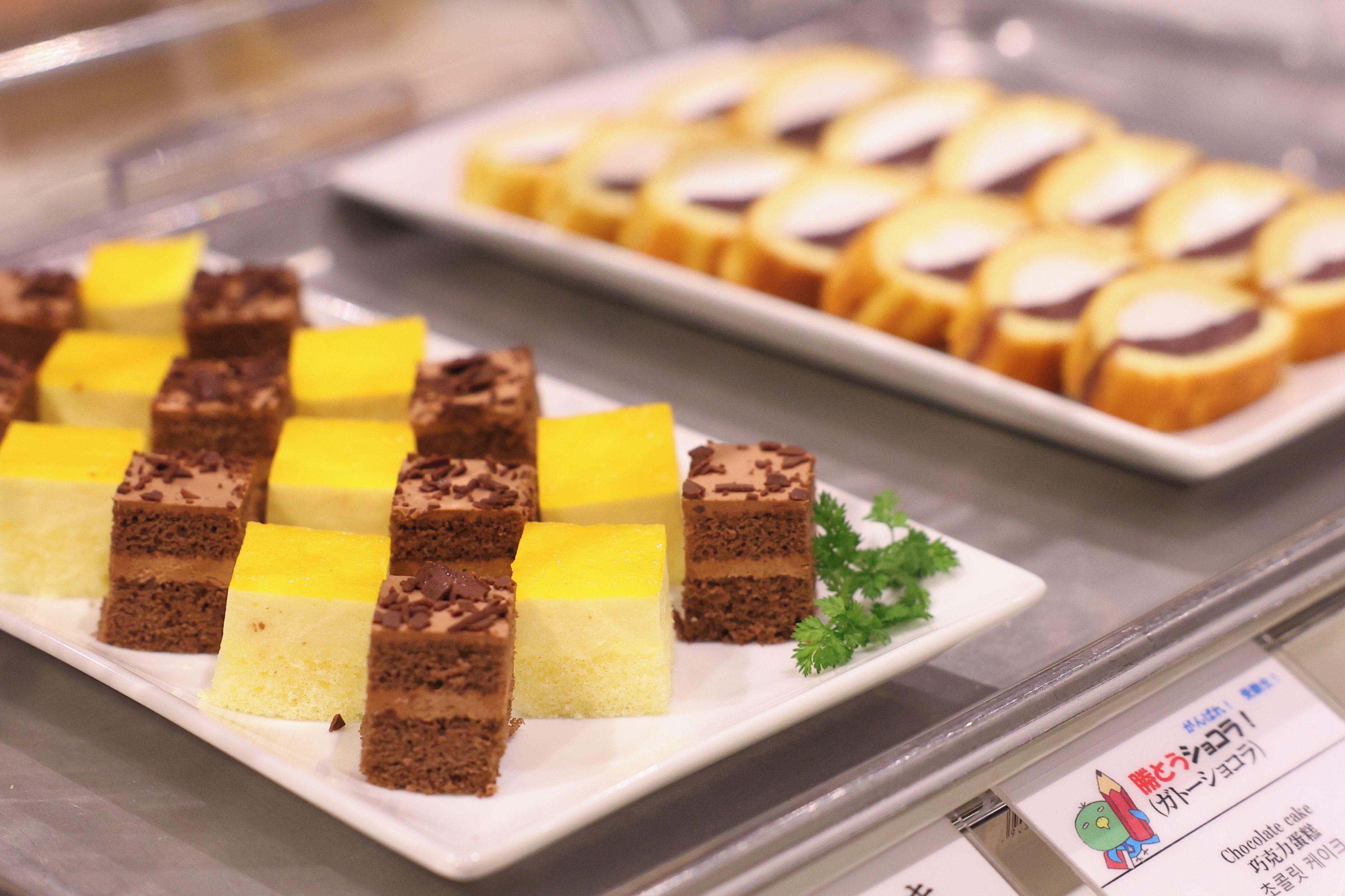 Een presentatie van diverse desserts, waaronder stukken chocoladetaart en gele cake, gepresenteerd op borden.