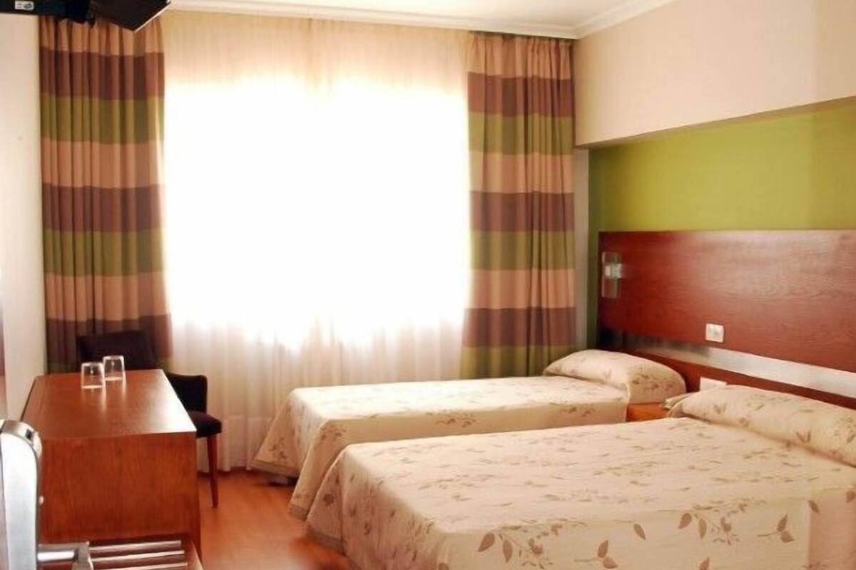 Ein Hotelzimmer mit zwei Betten, einem Schreibtisch und einem Fernseher.