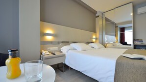 Una habitación de hotel con cama, mesita de noche y espejo.