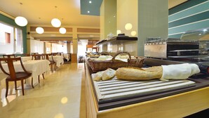 Un área de buffet con mesas, sillas y cestas de pan.