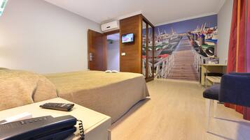 Habitació d'hotel amb llit, escriptori, televisió i un mural d'un port.