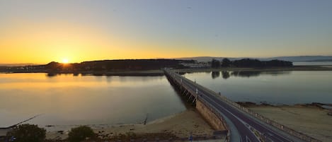 A bridge over a calm body of water during sunset.