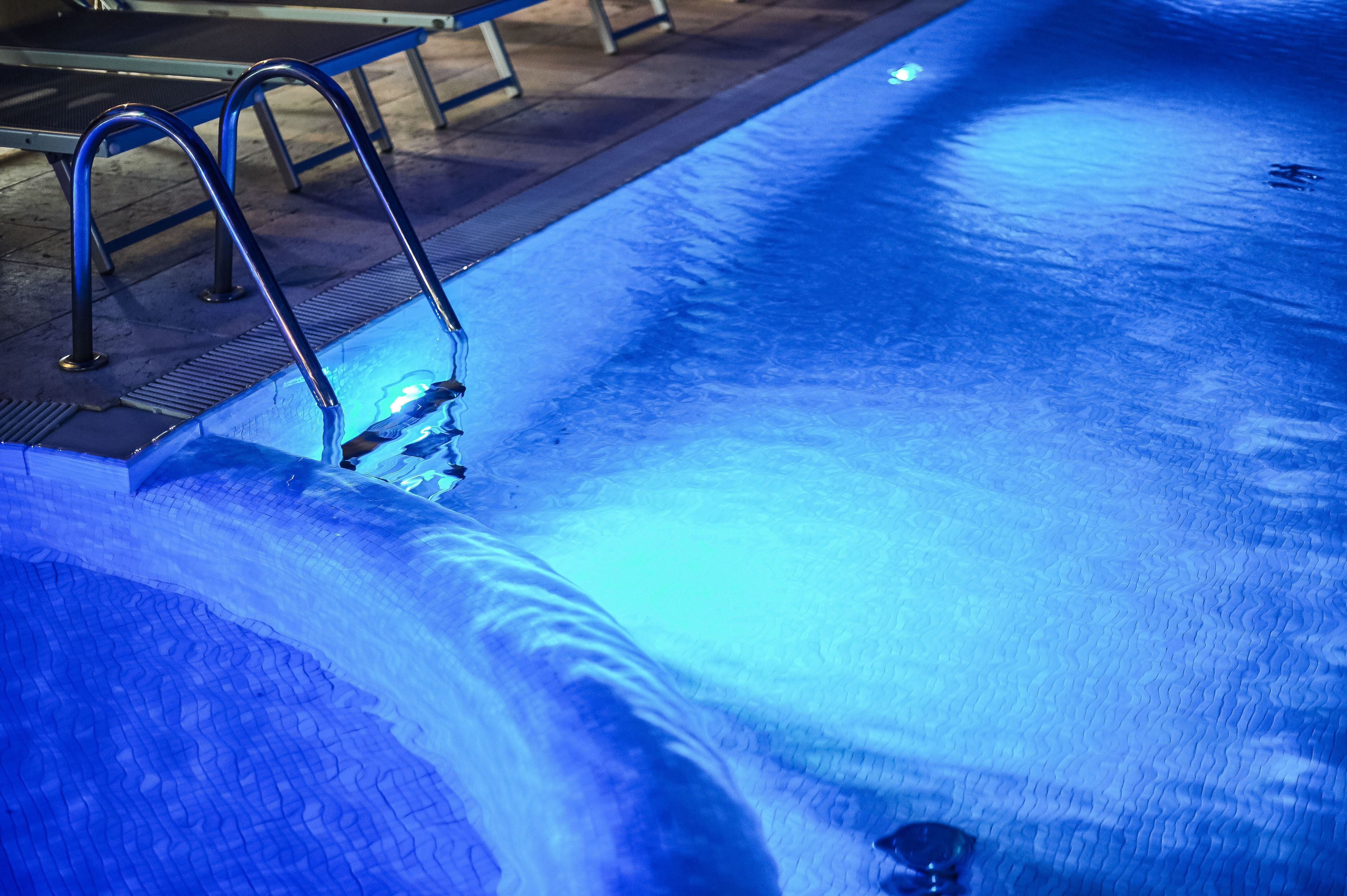 Ein Schwimmbecken mit Metallleitern und einer gefliesten Terrasse.