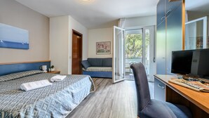 A modern hotel room with two beds, a desk, a TV, and a view of the outdoors. - Hotel Bella Venezia Mare (Lignano Sabbiadoro)