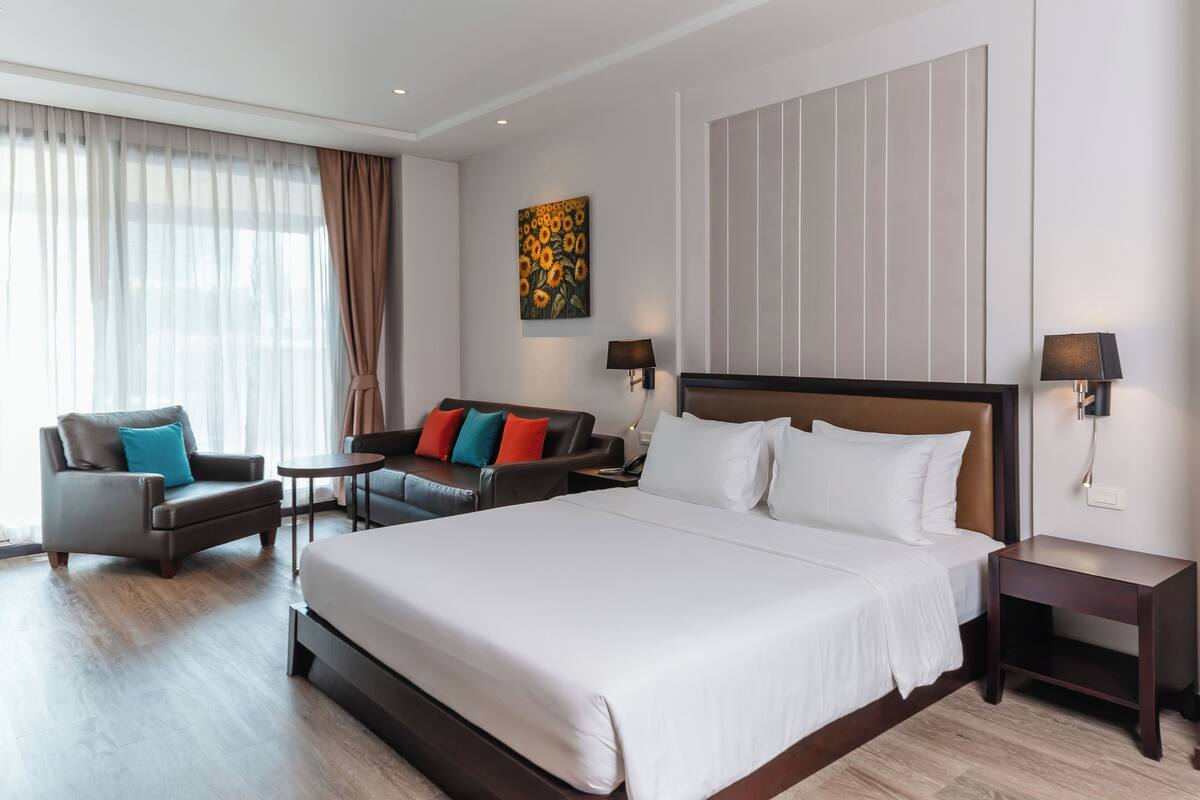 Een hotelkamer met een groot bed, een bank, een stoel, een tafeltje en een nachtkastje.