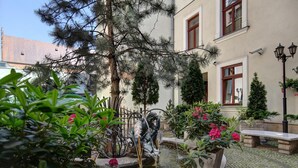 A courtyard with a fountain, potted plants, and a bench. - Hotel Wawel (Kraków)