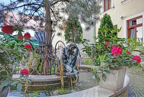 Una fontana con una statua, circondata da piante e fiori in vaso.