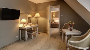A hotel room with a desk, chair, TV, lamps, and a small table with flowers. - Hotel Wawel (Kraków)