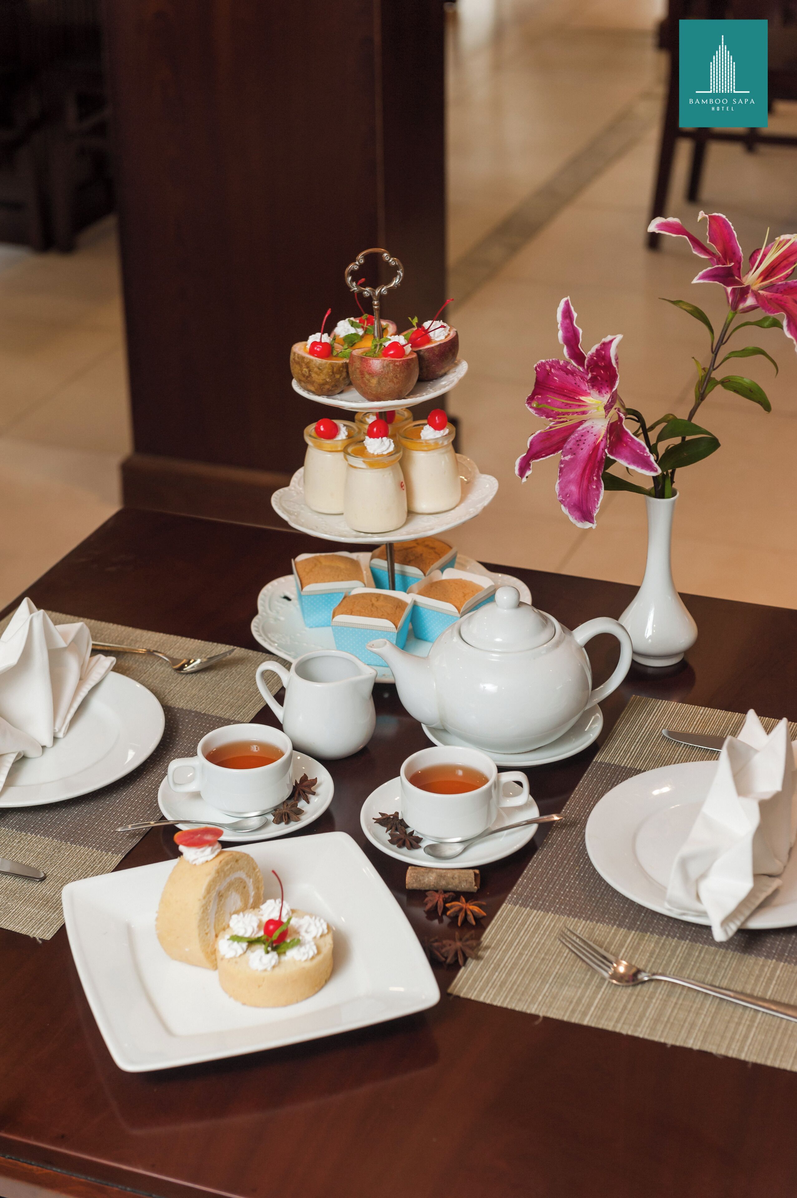 A table set for a tea service with multiple teapots, cups, and a tiered dessert display.
