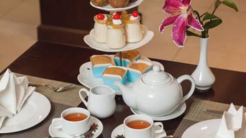 A table set for a tea service with multiple teapots, cups, and a tiered dessert display.