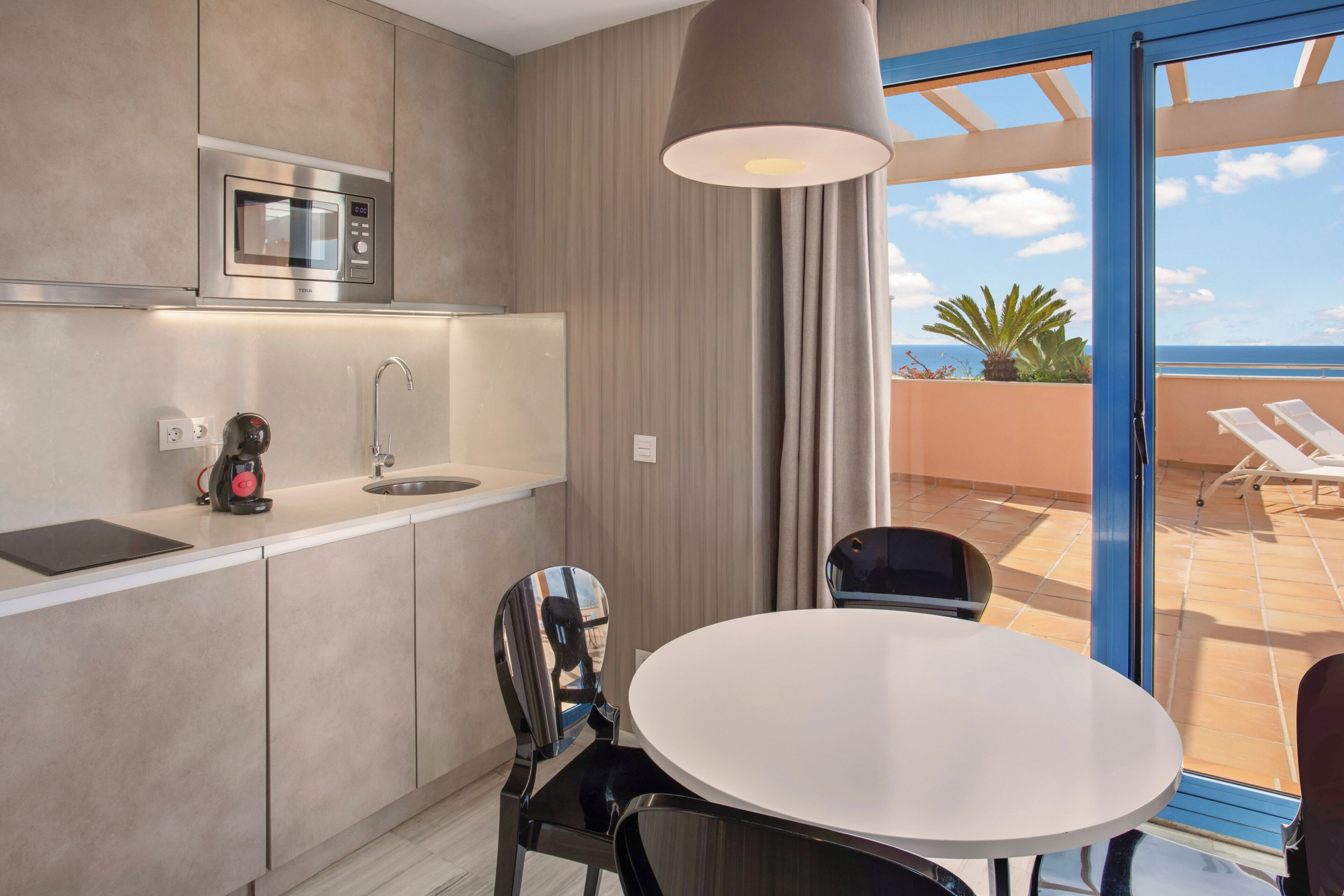 A modern kitchen with a microwave, coffee maker, and a dining area with a table and chairs.