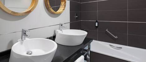 A modern bathroom with two white sinks, a bathtub, and two wooden-framed mirrors.