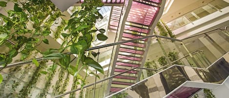 Ein mehrgeschossiges Interieur mit Glasgeländern, Pflanzen und modernem architektonischen Design.