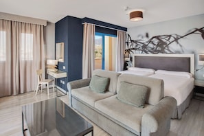 A hotel room with a bed, a sofa, a desk, and a chair.