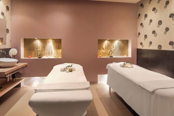 Un cuarto de spa con dos camillas, un lavamanos amplio y un espejo.