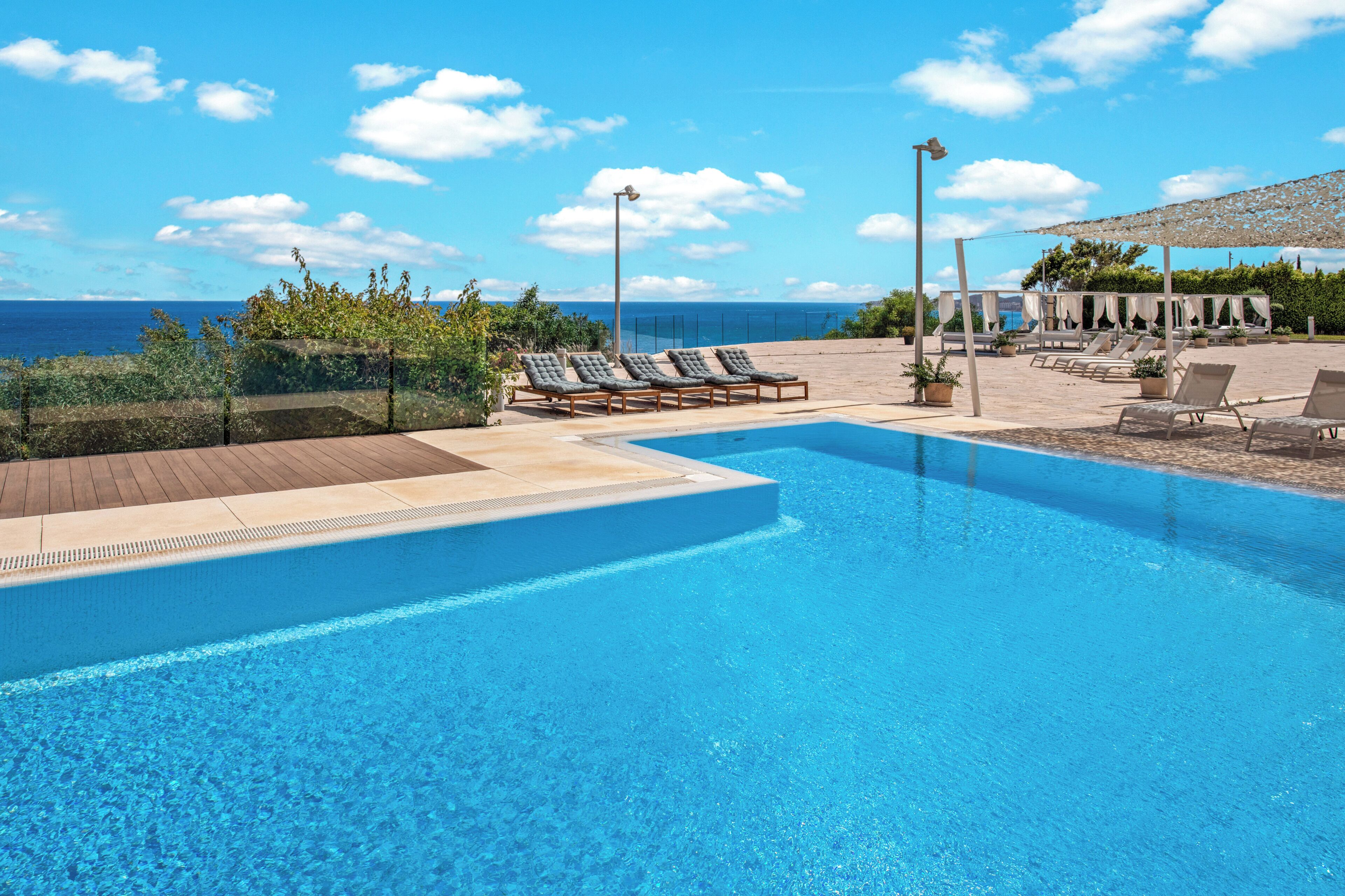 A swimming pool with lounge chairs and a view of the ocean.
