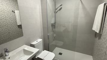 A modern bathroom with a glass-enclosed shower, a white sink, and a toilet.