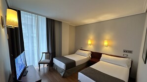 A hotel room with two beds, a desk with a computer, and a chair. - Hotel Compostela Vigo (Vigo)