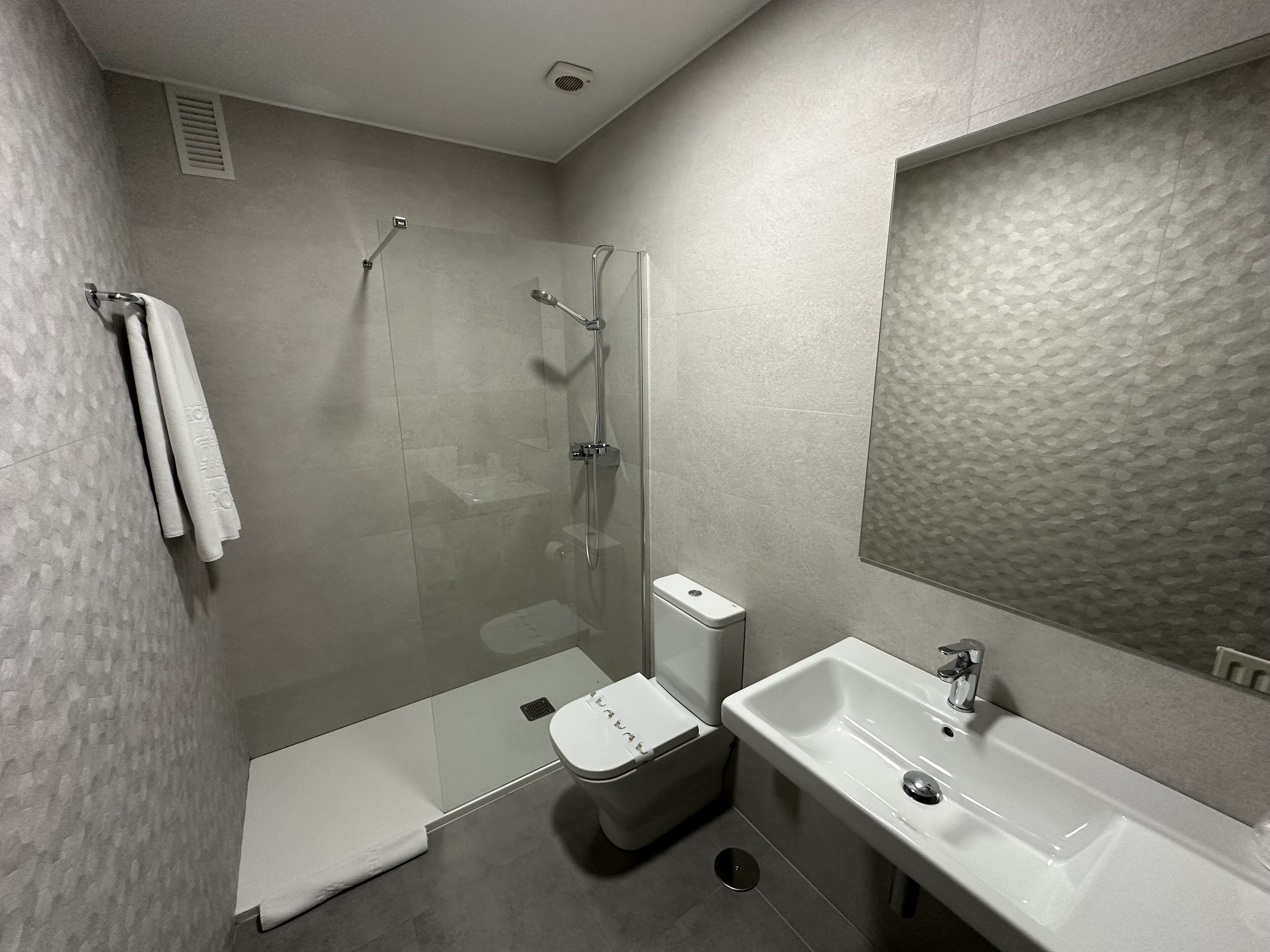 A modern bathroom with a glass-enclosed shower, a toilet, and a sink.