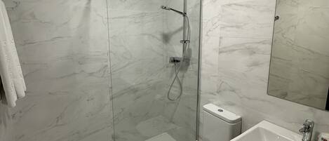 A modern bathroom with a glass-enclosed shower, a toilet, and a sink.