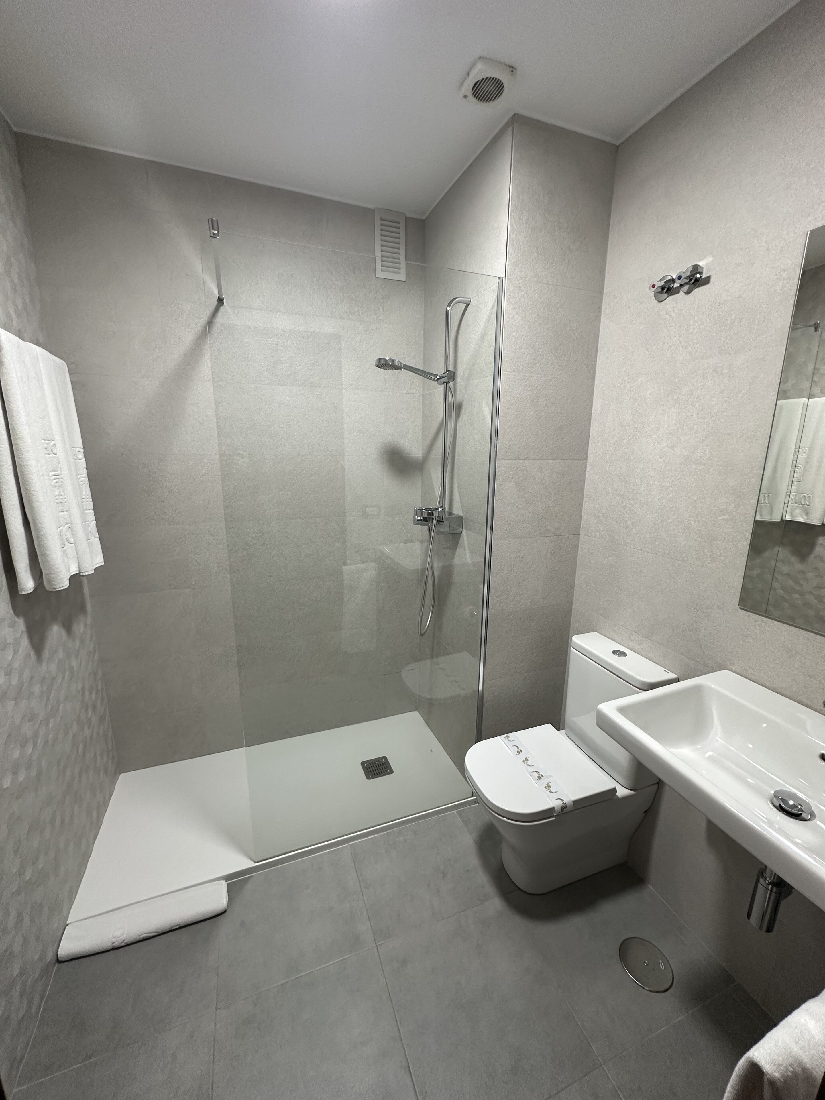 A modern bathroom with a glass-enclosed shower, a white toilet, and a sink.