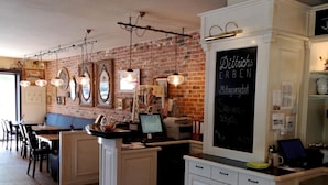 Un restaurant avec un mur en briques, des tables en bois et des lampes suspendues.