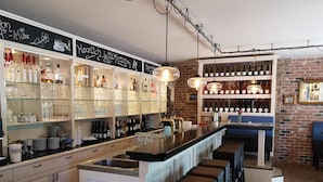 Un espace bar avec des étagères remplies de bouteilles et de verres, ainsi qu’un comptoir.
