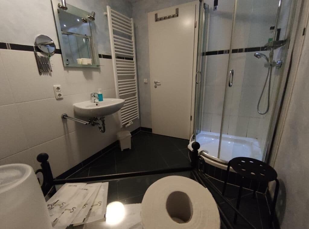 Un baño con inodoro, lavamanos, espejo, toallero, ducha y bañera.