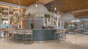 A modern bar area with a curved counter, bar stools, and pendant lighting.