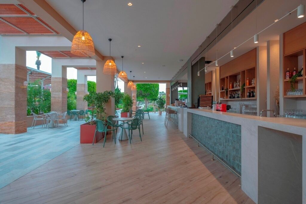 A spacious indoor area with a bar, seating, and potted plants.